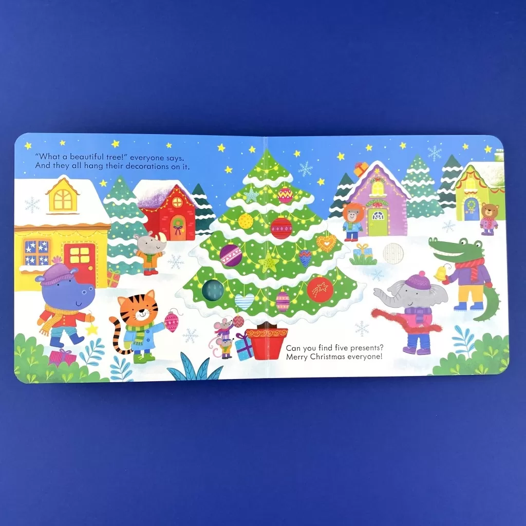 A photo of an interior spread in the book, showing a hippo, a tiger, a mouse, an elephant, an alligator a a bear around a Christmas tree.